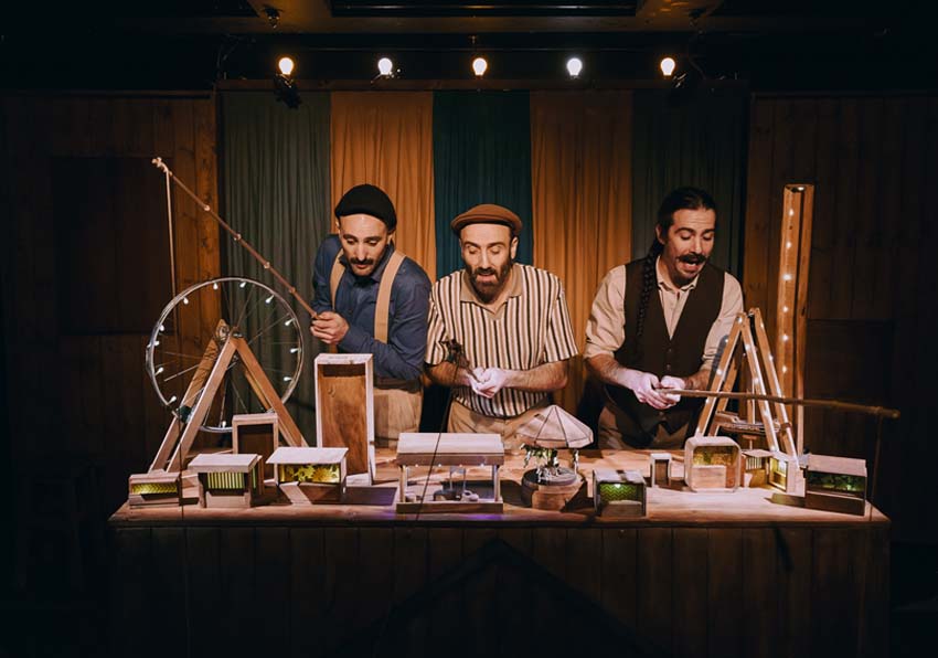 Three men behind a table with a model of a fair